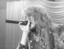 a woman is singing into a microphone while holding a telescope in her hand .