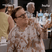 a man wearing glasses and a shirt that says mid century modern is standing in front of a bar