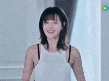 the woman is wearing a white tank top and black bra and smiling .