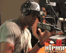a man wearing headphones and a hat stands in front of a microphone with the words hip hop nation below him