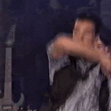 a man in a striped shirt is dancing with his arms outstretched .