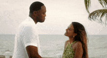 a man and a woman are looking into each other 's eyes on the beach