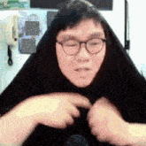 a man wearing glasses and a black scarf looks at the camera