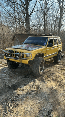 a yellow jeep is parked in a muddy area