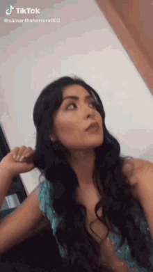 a woman in a blue dress is holding her hair in a ponytail ..