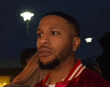 a man with a beard is wearing a red jacket and white collar