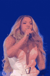 a woman in a white dress singing into a microphone with a belt around her waist