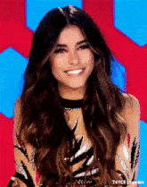a woman with long hair is smiling in front of a red background ..