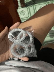 a person is holding a package of clear hair ties