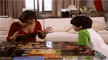 a woman in a red top is talking to a young boy who is playing a puzzle game