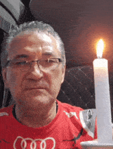 a man wearing glasses and a red shirt with the word audi on it