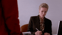 a woman sits at a desk with a pen in her hand