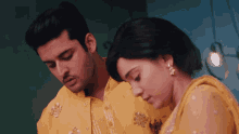 a man in a yellow shirt and a woman in a yellow dress look at each other