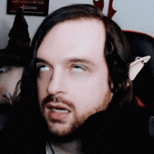 a man with long hair and a beard is making a funny face with his eyes closed