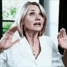 a woman in a white jacket is making a funny face with her hands outstretched .