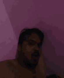 a man with a beard is taking a selfie with a purple background
