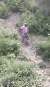 a man is walking down a dirt path in the woods with the caption `` when i go down hill '' .