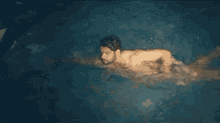 a shirtless man is swimming in a pool of water .