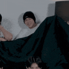 a man in a black beanie is laying on a black blanket