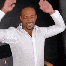a man in a white shirt is dancing with his arms outstretched and smiling .