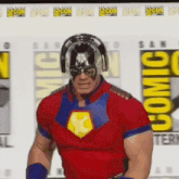 a man in a red and blue superhero costume is standing in front of a comic con sign