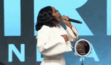 a woman is singing into a microphone in front of a mirror with the letter n on it