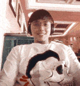 a man wearing headphones and a shirt with a skull on it smiles for the camera