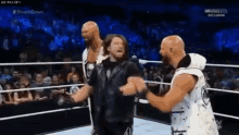 a group of wrestlers are standing in a wrestling ring with a crowd watching .