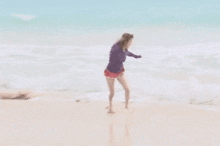 two women are hugging on the beach and one has a purple shirt on