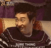 a man in a sweater is sitting on a couch making a funny face .