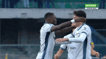 a soccer player wearing a bets jersey is hugging another player on the field