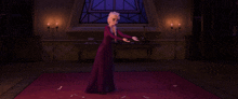 a woman in a purple dress is standing in a room with candles