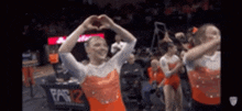 a group of gymnasts are making a heart with their hands .