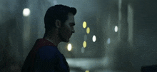 a man in a superman costume stands in a dark room