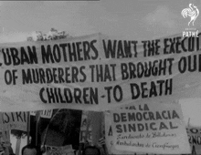 a black and white photo of people holding signs that say cuban mothers want the execution of murderers that brought our children-to death