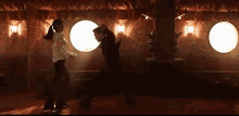 a man is kicking another man in the leg in a dark room with a lot of lights .