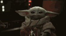 a baby yoda from star wars is sitting in a dark room .
