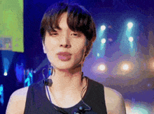 a young man is wearing a black tank top and headphones while standing on a stage .