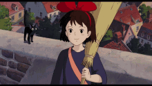 a girl with a red bow on her head is holding a broom in front of a black cat