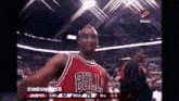 a basketball player in a bulls jersey stands in front of a crowd