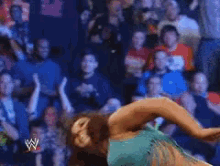 a woman in a green dress is holding a wrestling championship belt in front of a crowd