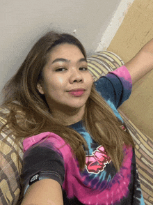 a woman in a tie dye shirt is laying on a couch with her arm outstretched