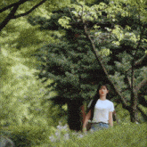 a woman in a white t-shirt stands in a forest