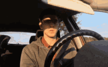 a man wearing glasses is driving a car with his eyes closed