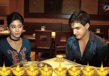 a man and woman are sitting at a table with candles on it
