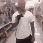 a man in a white shirt is holding a gun on his shoulder .