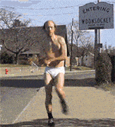 a shirtless man in white underwear is running in front of a sign that says entering moonsocke