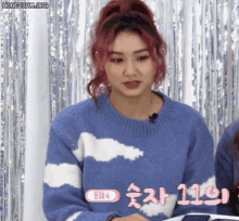 a girl with red hair wearing a blue sweater with white clouds