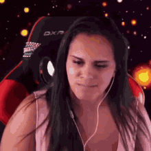 a woman is wearing headphones and sitting in a dxr chair