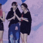two girls standing next to each other on a stage with a microphone